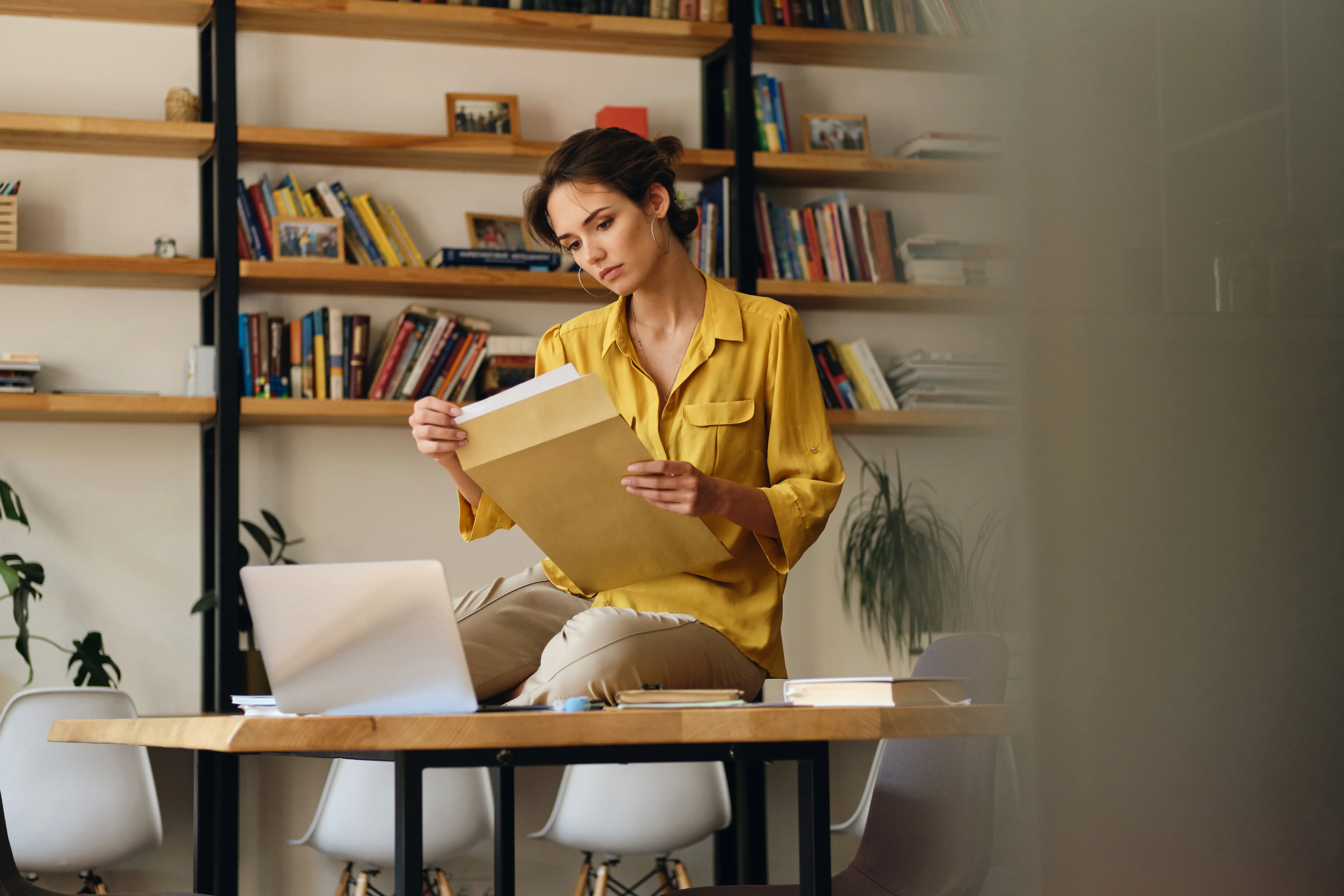 beautiful-woman-in-shirt-sitting-on-desk-with-docu-2022-02-02-04-51-47-utc.webp